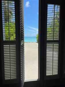 sand and ocean viewed through open shutters